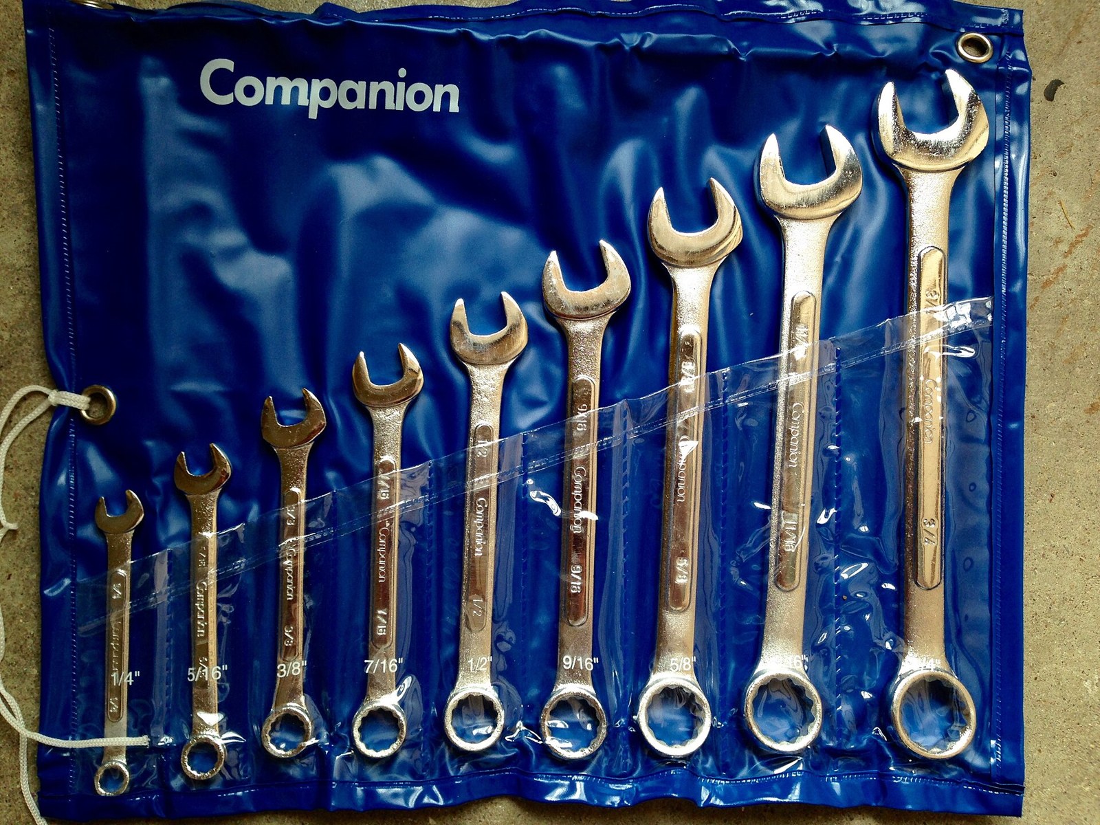 Nine combination wrenches graded by size in a blue tool roll