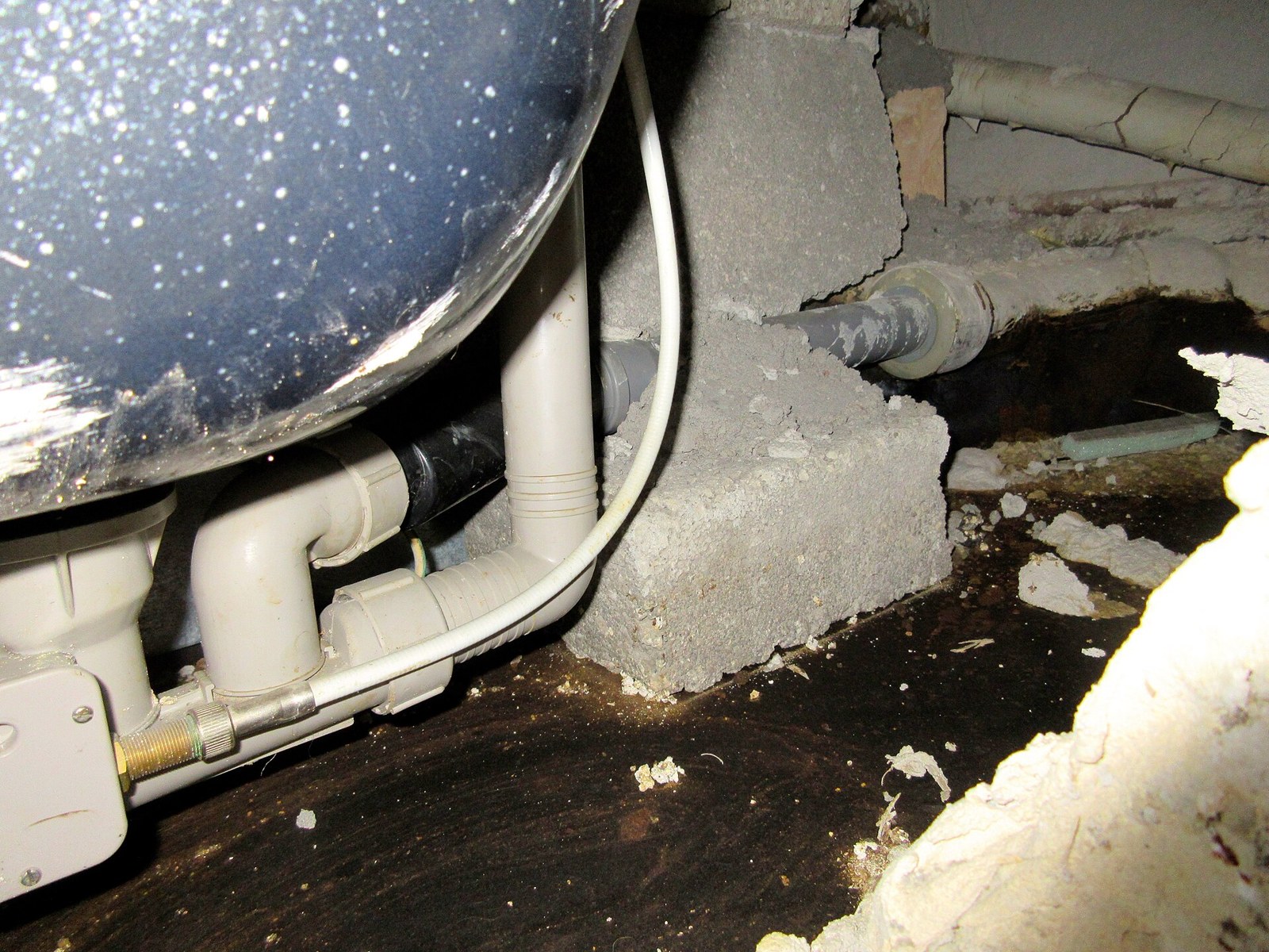 A bath waste pipe and trap exposed below floor level