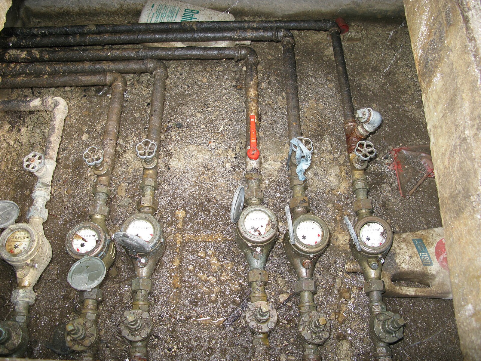 A row of six water meters and isolation valves in a below-ground meter chamber